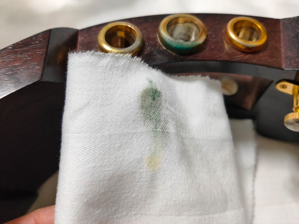 青サビ（緑青）を取るために研磨剤を付けた布で津軽三味線の福林を磨く